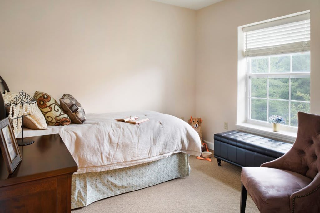 A cozy bedroom with a bed and a window bench.