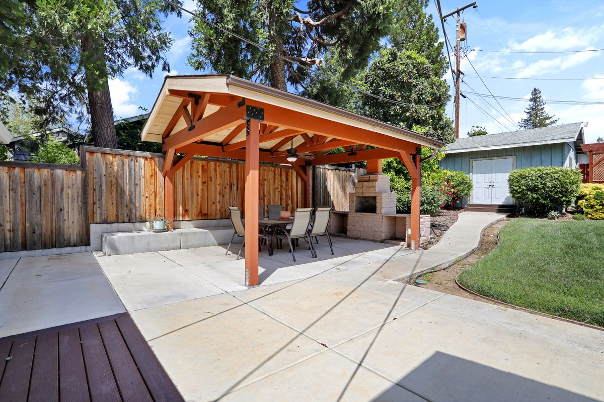A backyard patio with a wooden pergola and outdoor seating.