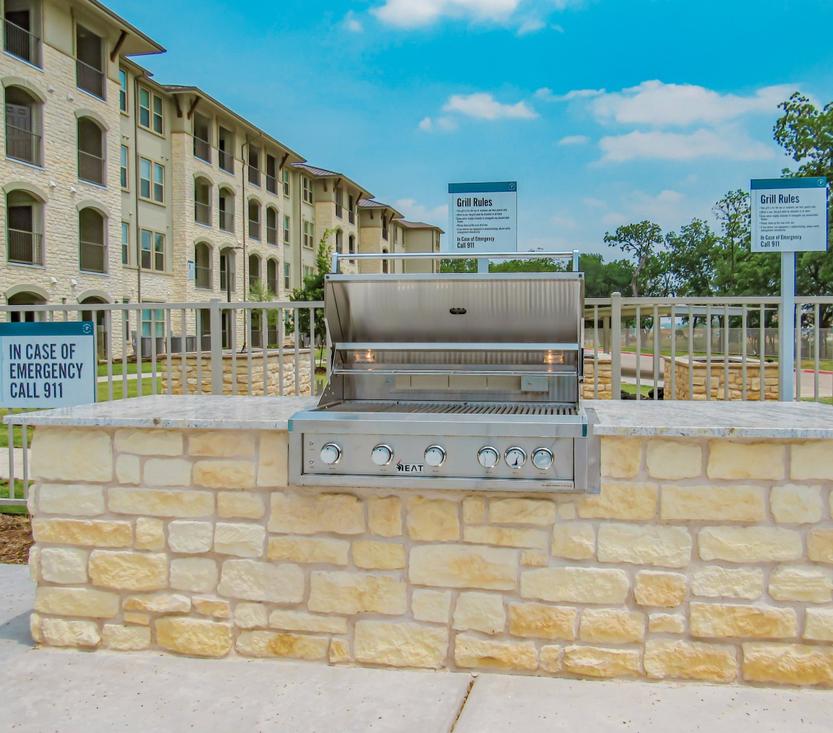 An outdoor barbecue grill situated in a stone patio area of an apartment complex.