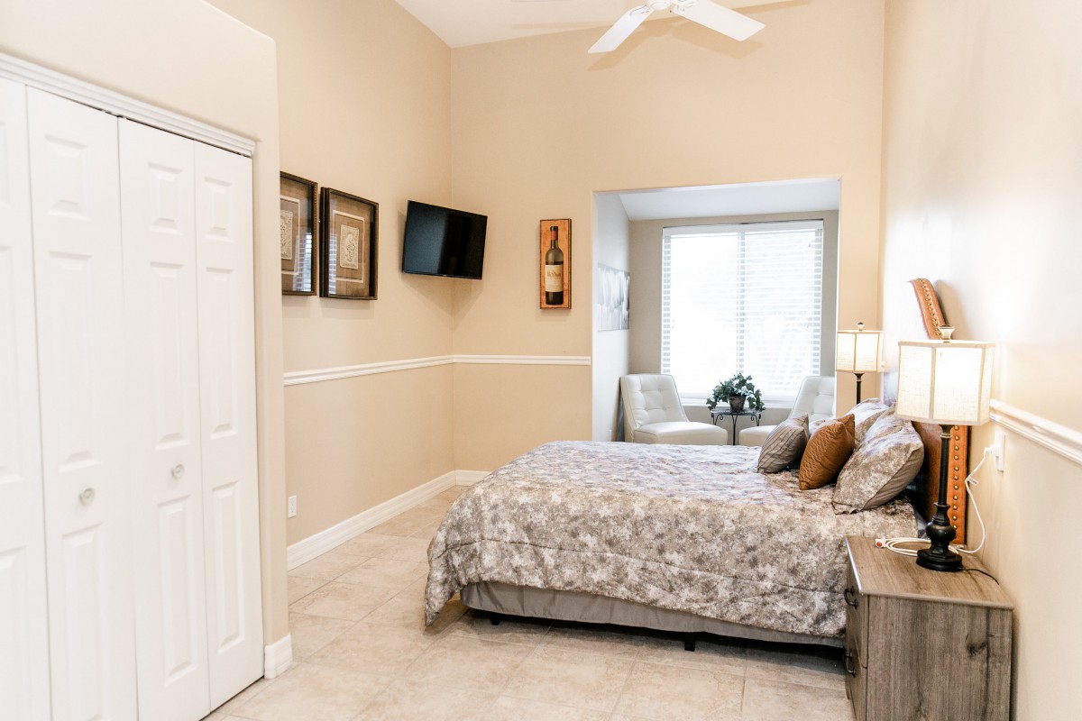 A cozy bedroom featuring a bed, television, and window seating area.
