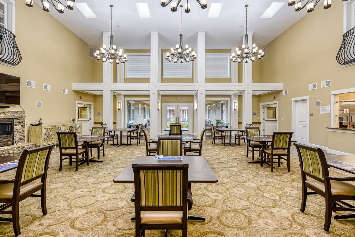 A spacious and modern dining area with multiple tables and elegant chandeliers.