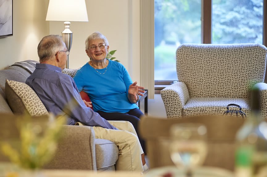 Two seniors enjoying a conversation in a cozy living room setting.