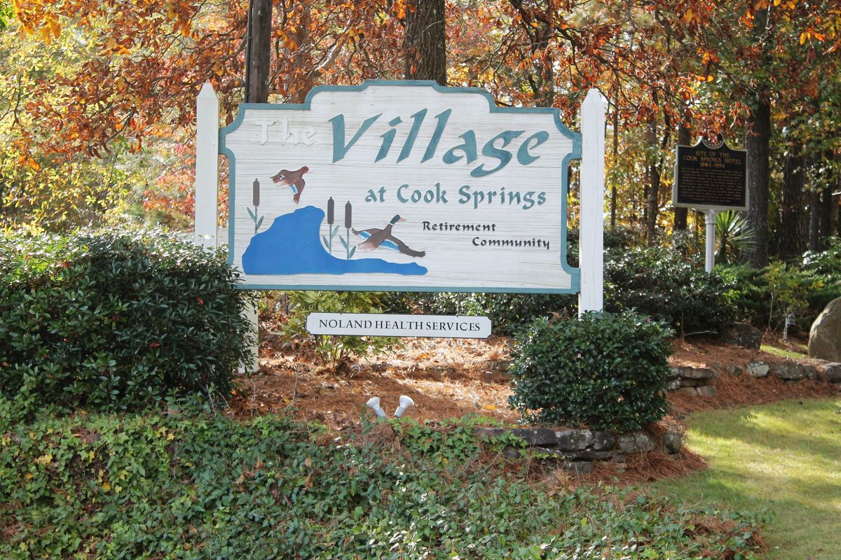 Sign for Village at Cook Springs surrounded by autumn foliage.