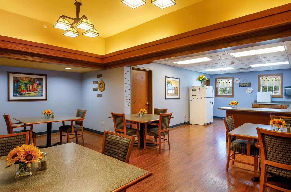 A cozy dining area with tables and chairs adjacent to a kitchen space.