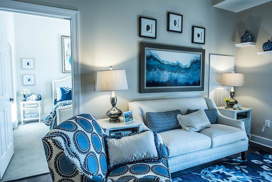 A stylish living room featuring a comfortable sofa, patterned armchair, elegant wall art, and warm lighting.
