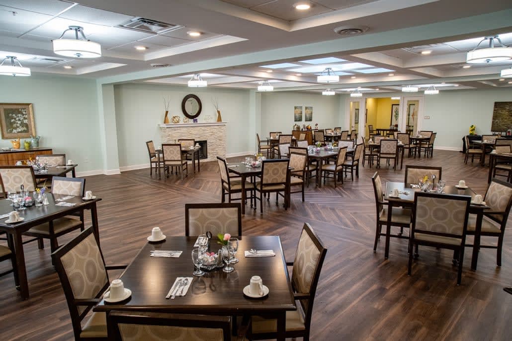An elegantly designed dining area with multiple tables and chairs, featuring a wooden floor and stylish lighting.
