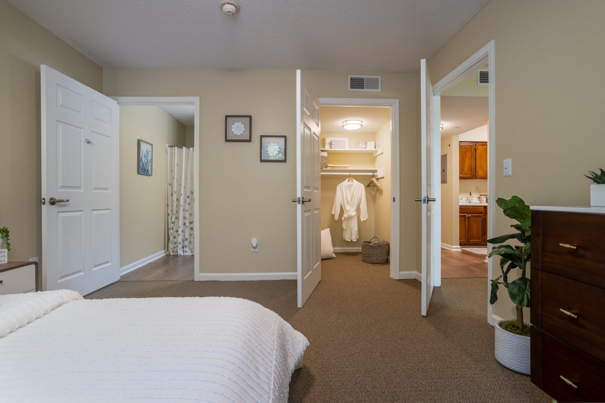 A cozy bedroom with an open view of the closet and adjacent rooms.