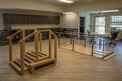A well-equipped rehabilitation room featuring a set of parallel bars and a wooden ramp designed for physical therapy exercises.