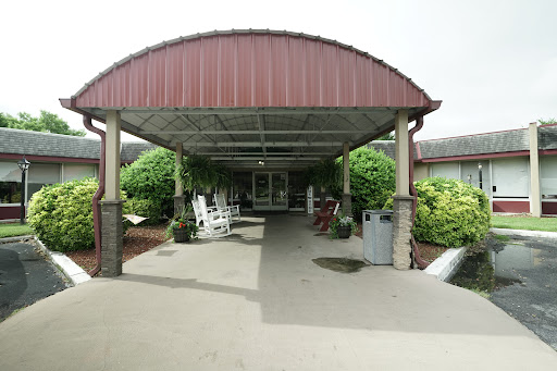 A welcoming entrance to a building, featuring a covered walkway and rocking chairs.