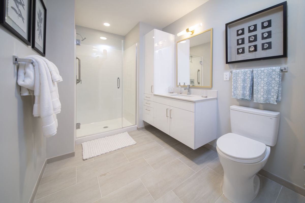 A modern, minimalist bathroom with sleek white fittings and a spacious shower area.