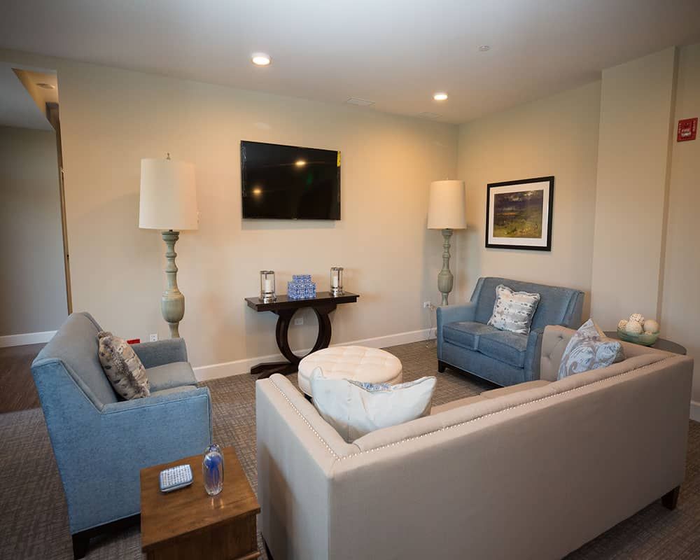 A cozy living room with sofas, a wall-mounted television, and decorative lamps.