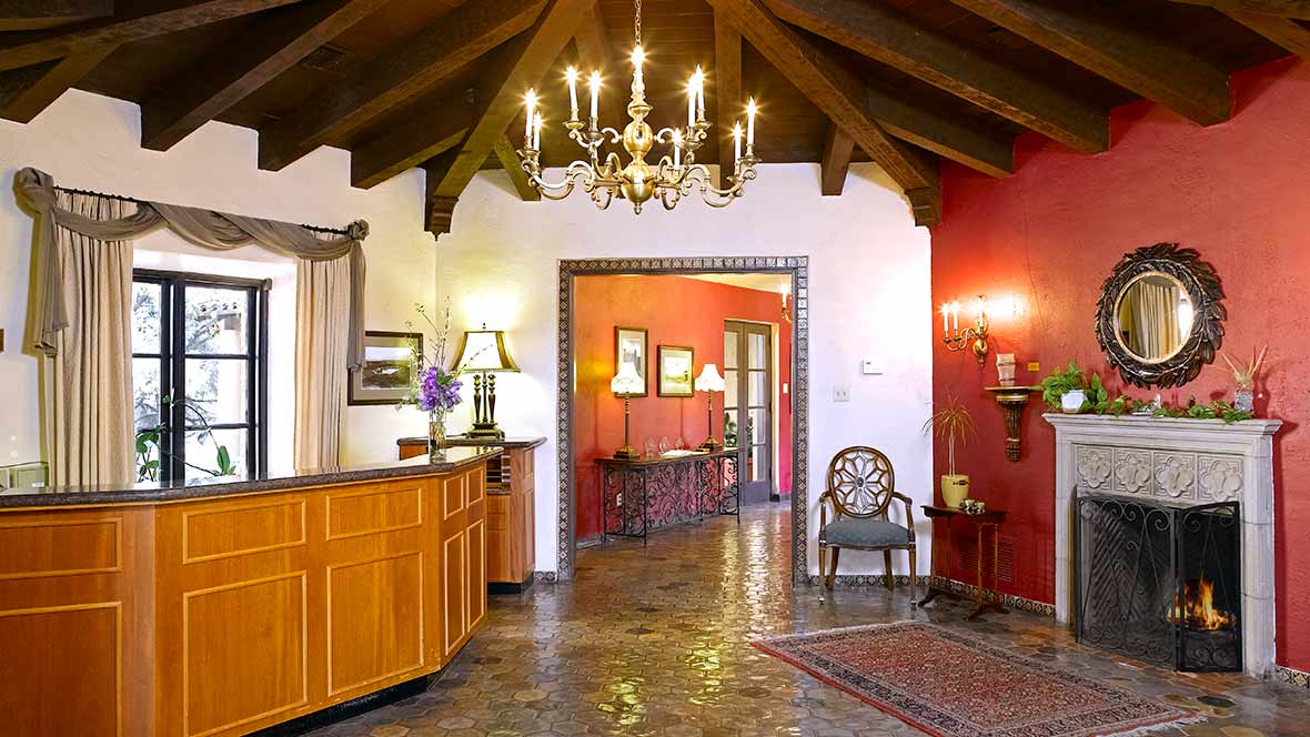 A traditional lobby area with a chandelier, wooden beams, and elegant furniture.