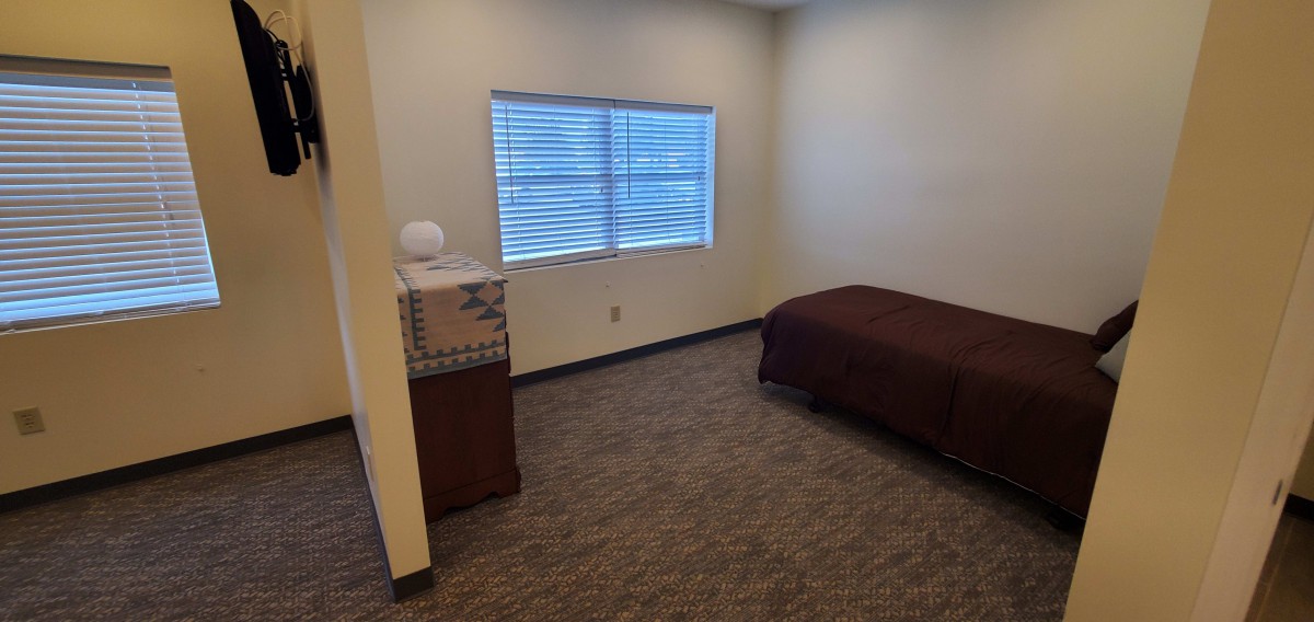 A small, minimalist bedroom with a bed, window, and simple decor.