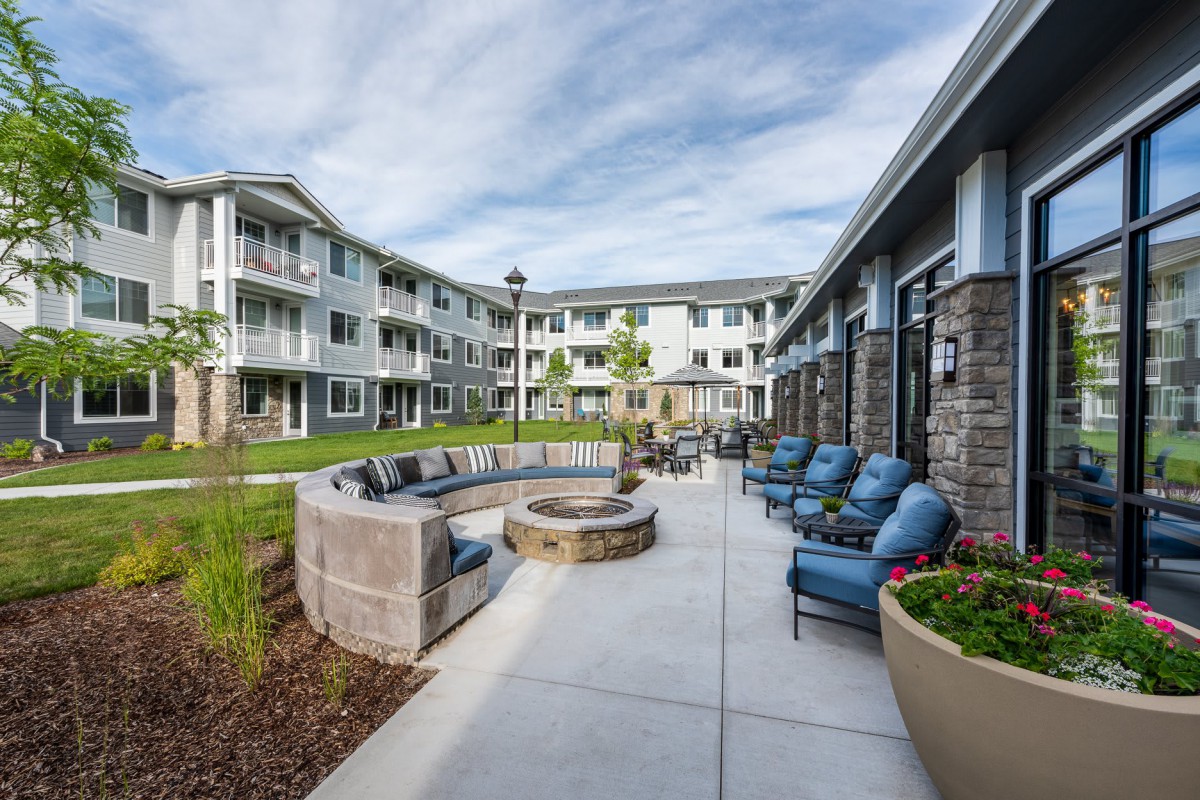 A modern apartment complex featuring a landscaped courtyard with seating and a fire pit.