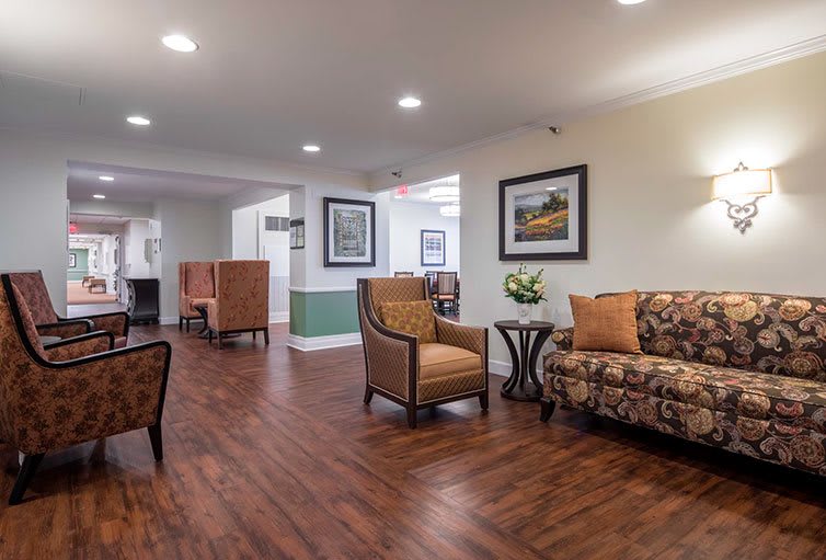A well-lit lobby area featuring comfortable seating with a sofa and armchairs, complemented by wooden flooring and decorative artwork.