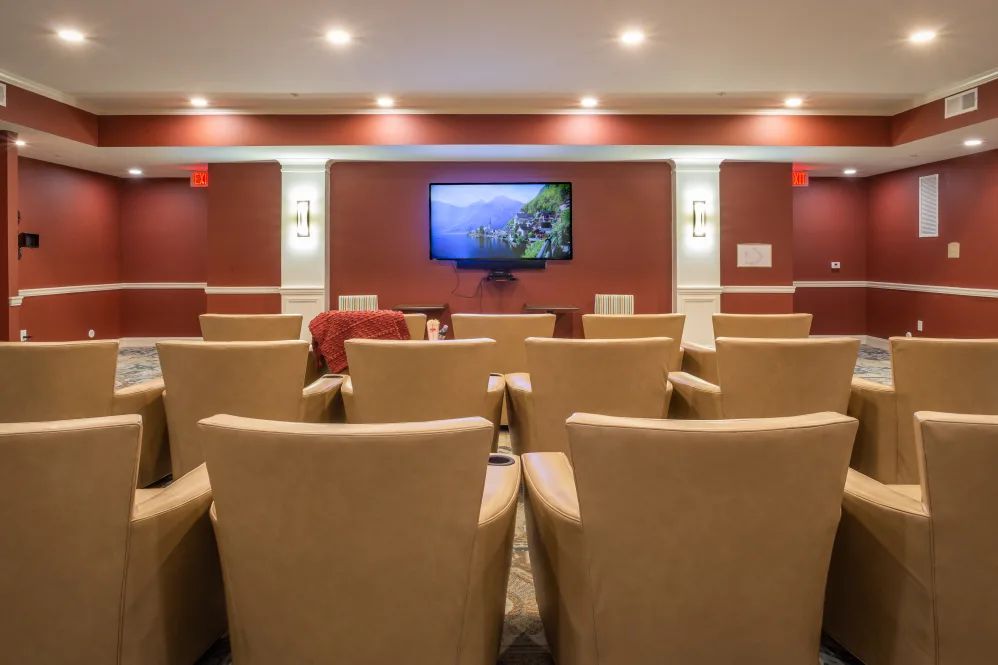 A small theater room with rows of comfortable chairs facing a large screen.