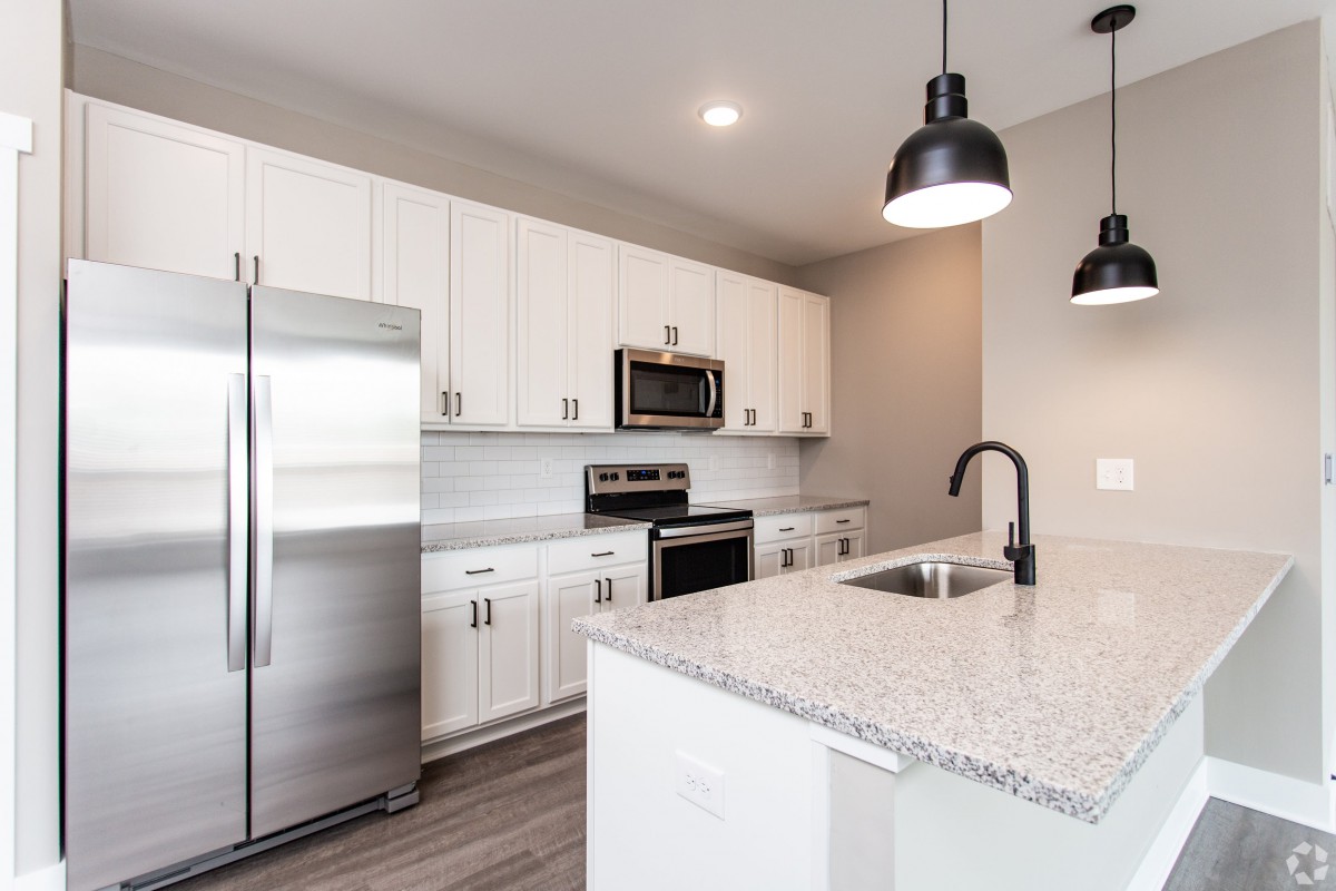 Modern kitchen with white cabinets and stainless steel appliances.