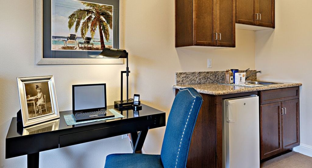 A cozy home office setup featuring a desk, chair, laptop, and lamp.