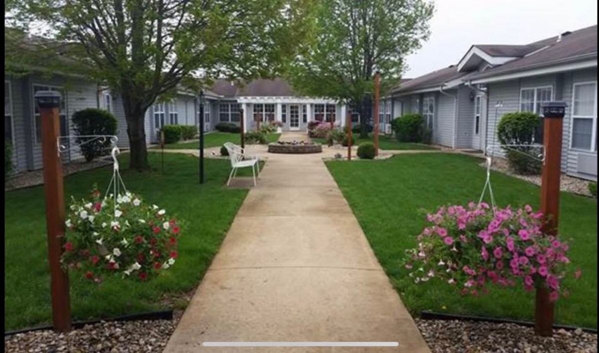 A serene courtyard featuring a central walkway surrounded by lush greenery and seating areas.
