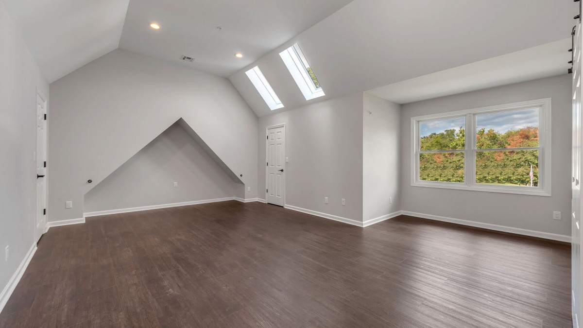 A spacious attic room with hardwood floors and skylights.