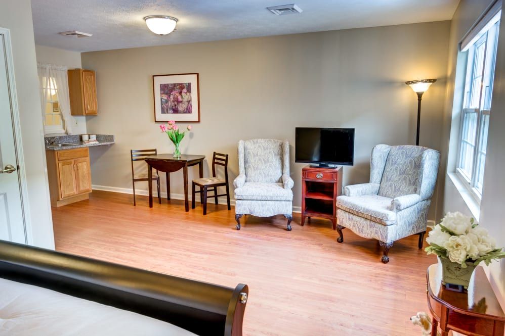 A cozy living room with elegant chairs, a small dining table, and a television.