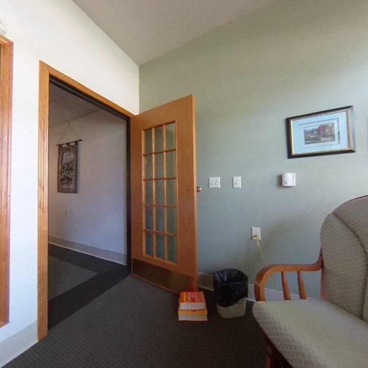 A room with a sofa, an open door, and a framed picture on the wall.