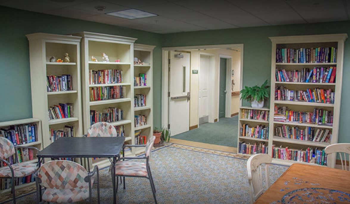 A cozy library corner with bookshelves, tables, and chairs.