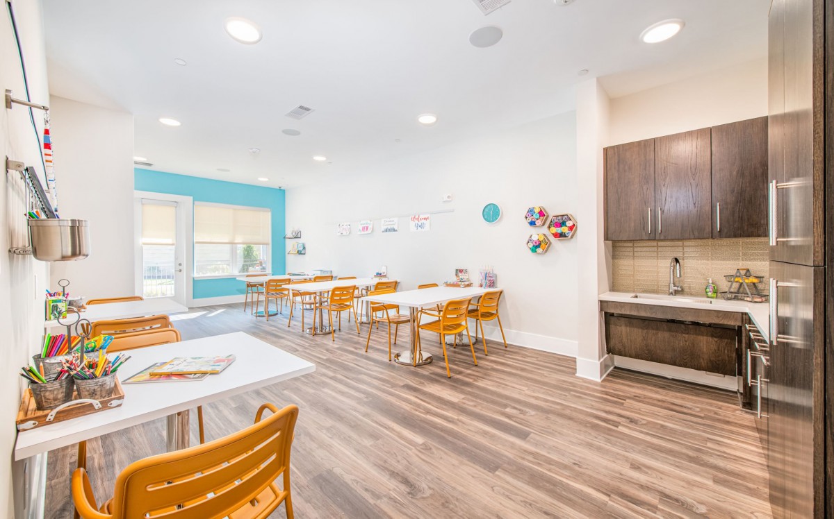 A bright and modern classroom with tables, chairs, and art supplies.