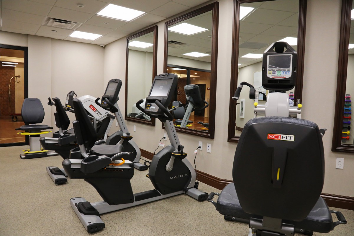 A well-equipped gym room featuring multiple exercise bikes and large mirrors.