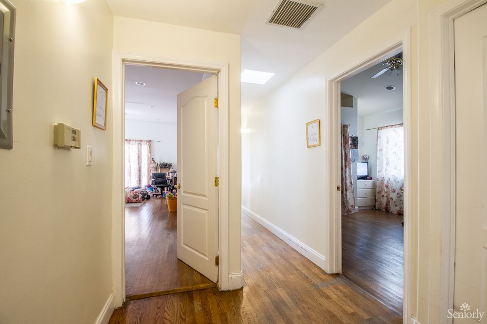 A hallway in a home with wooden flooring and doors leading to different rooms.