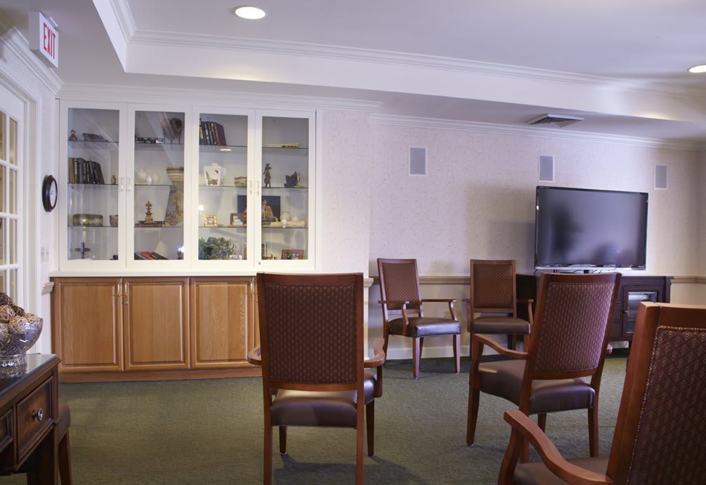 A spacious meeting room with chairs arranged around a television and display shelves.