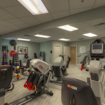 A well-equipped gym room with various fitness machines and weights.