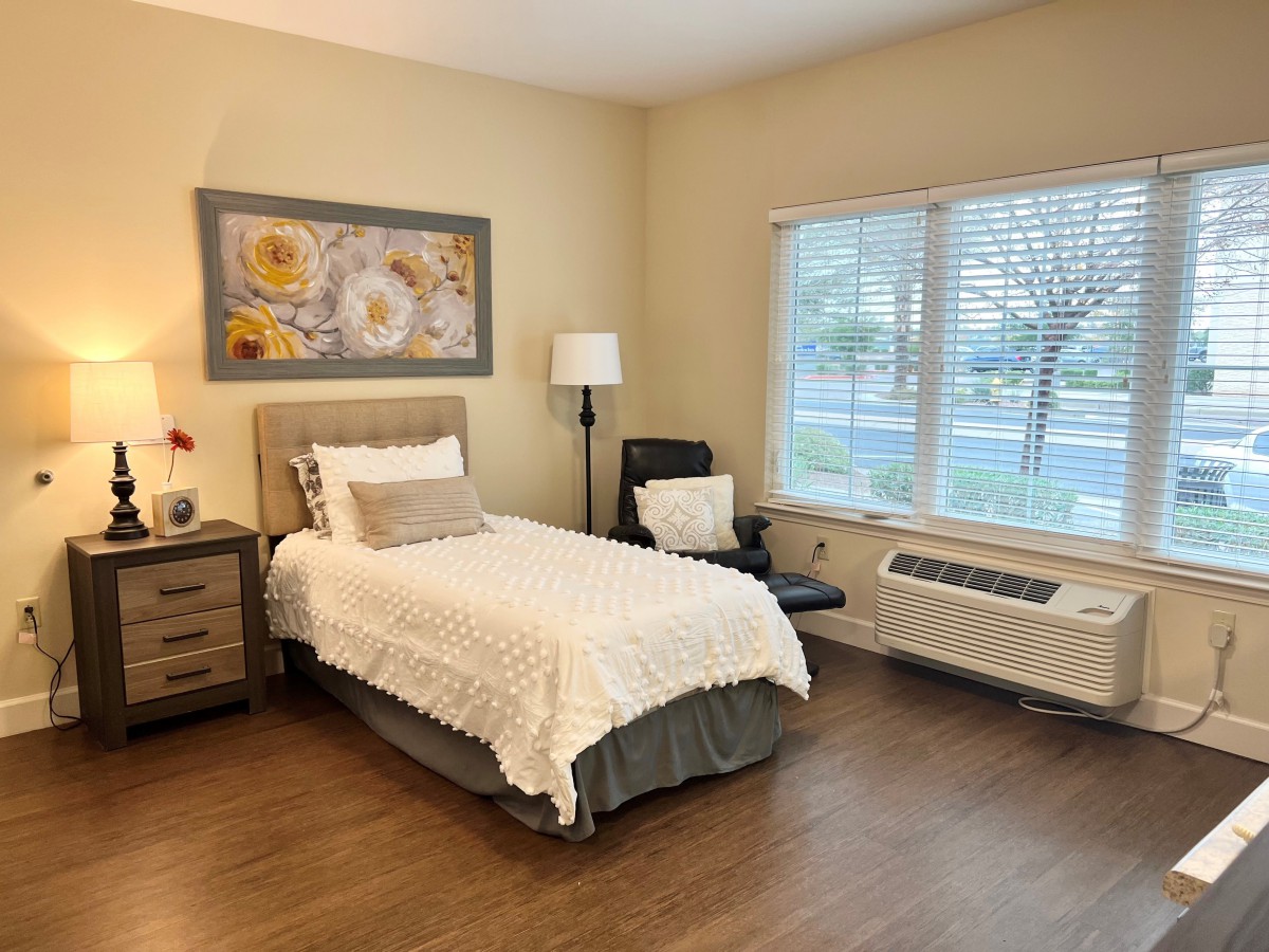 A cozy bedroom with a single bed, nightstand, and artwork on the wall.