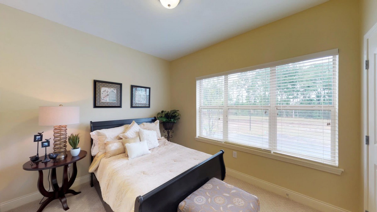 A cozy bedroom with a neatly made bed and large window providing natural light.