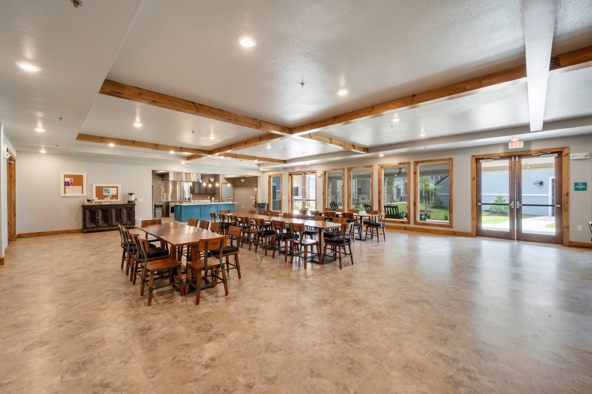 Spacious dining area with multiple tables and chairs, large windows, and bright lighting.