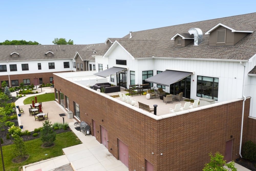 A modern residential building featuring a spacious rooftop patio with outdoor seating and landscaped surroundings.
