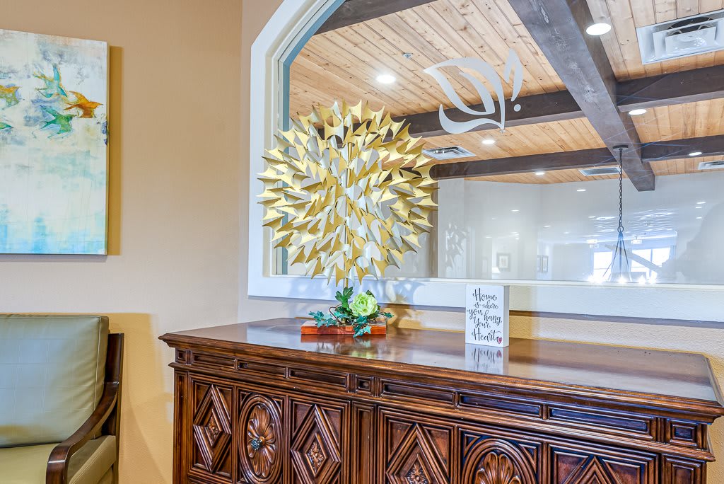 A beautifully decorated interior with a wooden cabinet, adorned with a gold ornament and a mirror, reflecting the rustic ceiling beams and antler decoration.