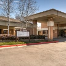 Entrance to a healthcare facility with a parking area.