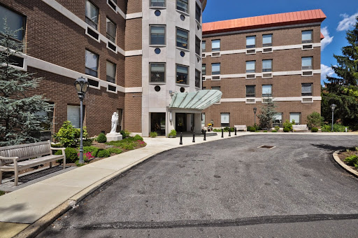 A welcoming entrance to a residential building, featuring well-maintained landscaping and a clear blue sky.