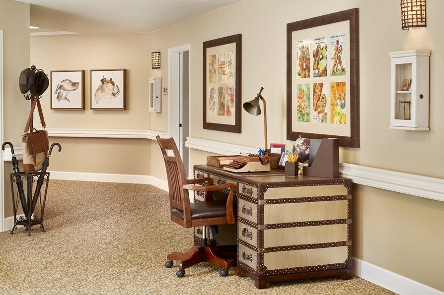 A cozy office space with a vintage desk and chair, adorned with artistic wall decor.