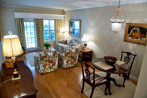 A cozy and elegantly decorated living room with floral-patterned furniture, a dining area, and ample natural light.