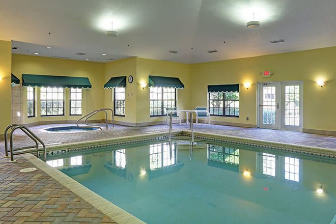 An indoor swimming pool area with large windows and ambient lighting.