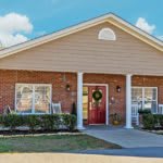 A cozy brick house with a welcoming front porch and decorative columns.