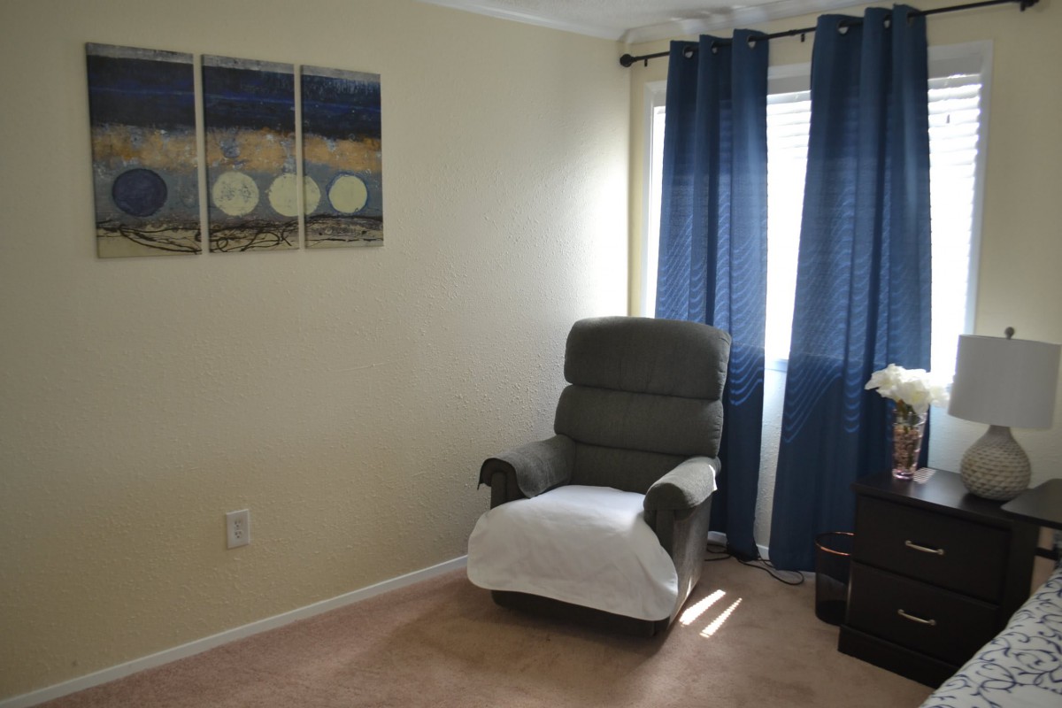 A cozy living room corner with an armchair and blue curtains.