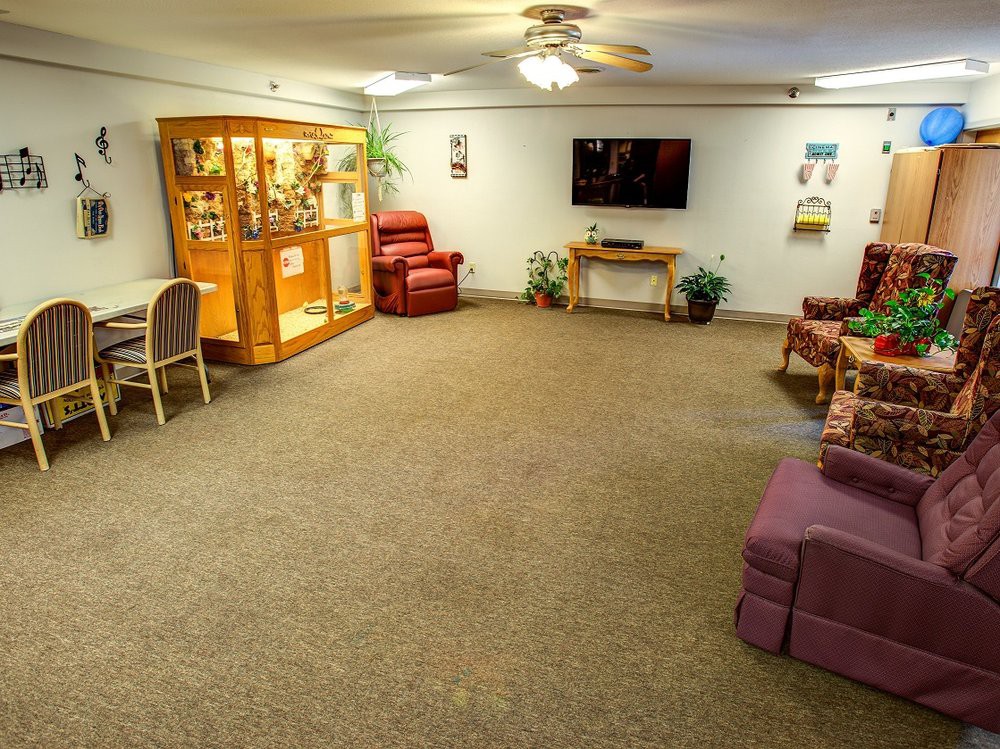 A cozy living room with seating, a television, and a display cabinet.