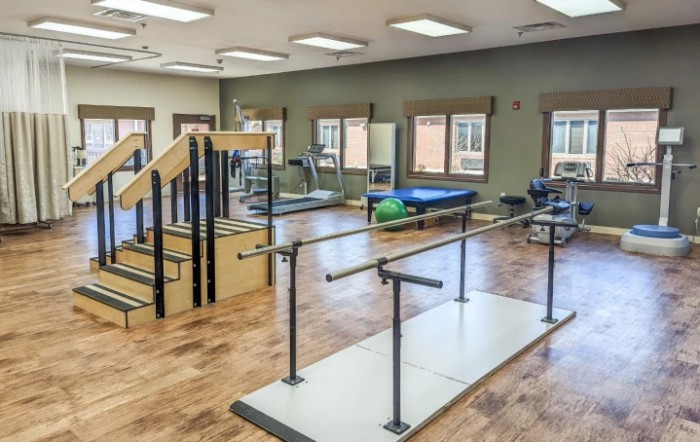 A rehabilitation center equipped with various physical therapy tools, including parallel bars and a staircase for mobility exercises.