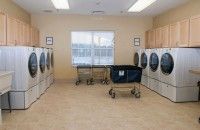 A clean and organized laundry room with multiple washing machines and laundry baskets.