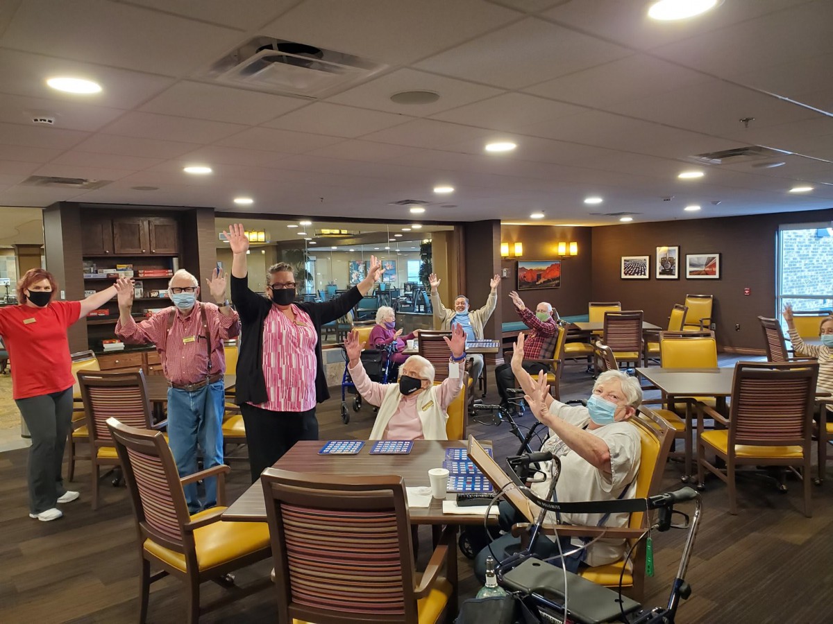 A group of seniors participating in an indoor social gathering, some wearing masks.
