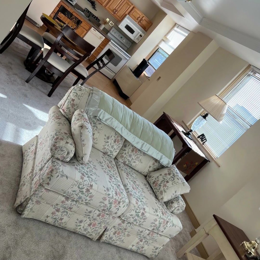 A cozy living room with a floral sofa, dining area, and open kitchen.
