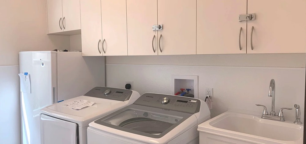 A laundry room featuring a washing machine and dryer beneath overhead cabinets.